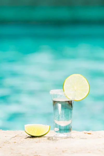 Tequila shot con calce su sfondo blu — Foto Stock