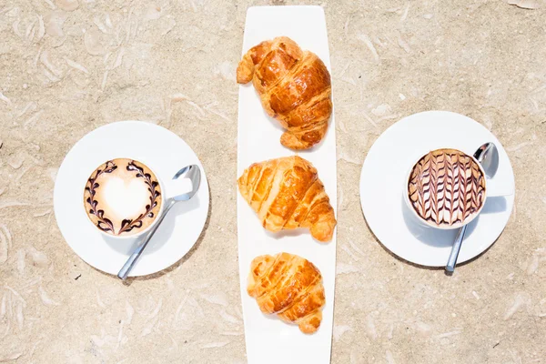 Dos tazas de café con arte latte y croissants — Foto de Stock