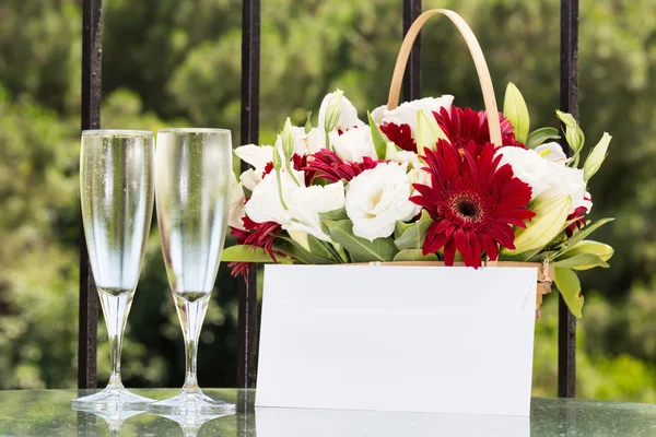 Two glasses of champange and flower basket with plain envelope