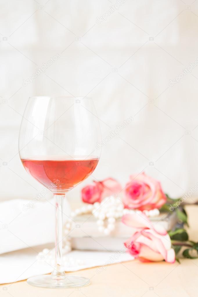 Glass of rose with vintage books and pearls