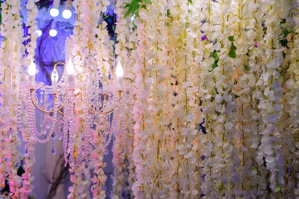 Chandelier hangs among the hanging flowers — Stock Photo, Image