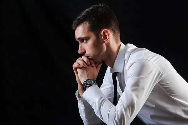 Un uomo in camicia bianca con cravatta su sfondo nero — Foto Stock