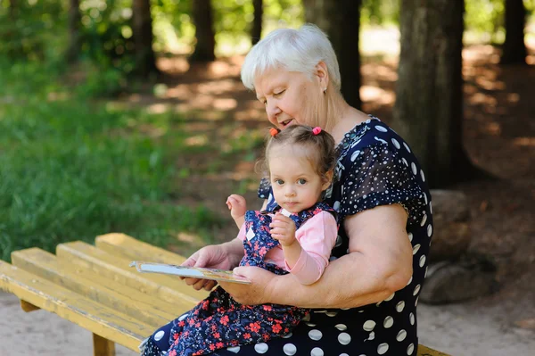 Grandmother and granddaughter reading the book in the park — Stock Photo, Image