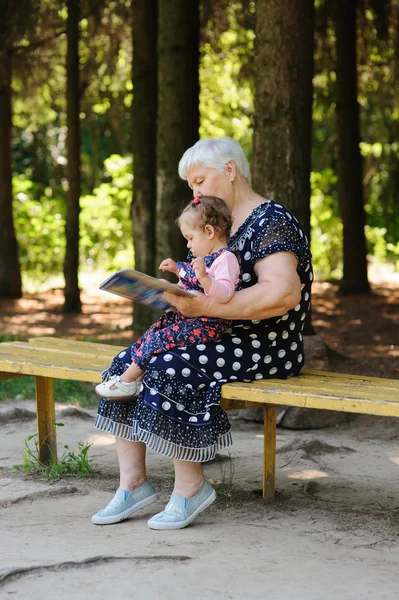 Grandmother and granddaughter reading the book in the park — Stock Photo, Image