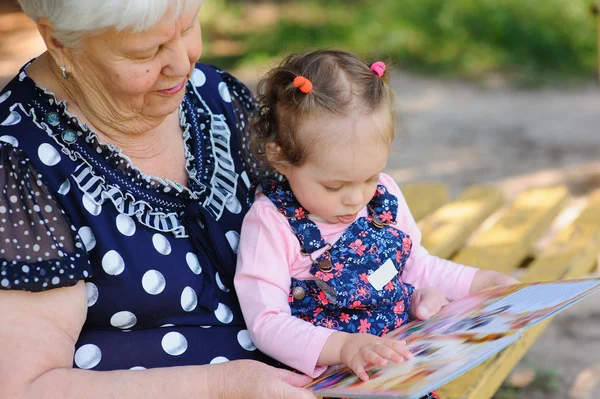 Бабушка и внучка читают книгу в парке — стоковое фото