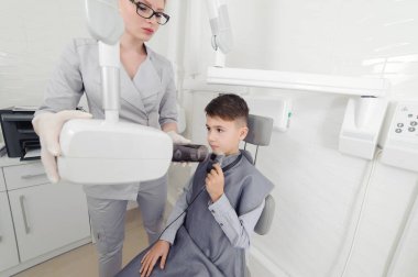 Diş hekimi elleri, diş kliniğindeki küçük çocuk için çene röntgeni görüntüsü oluşturur