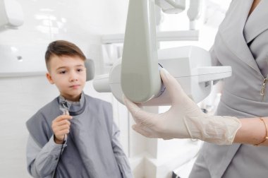 Diş hekimi, diş kliniğindeki küçük çocuk için çene röntgeni görüntüsü hazırlar