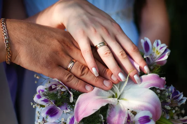 Dwie ręce z obrączki ślubne i kwiaty — Zdjęcie stockowe