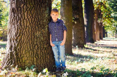 Bir ağacın yanında poz şık sevimli çocuk