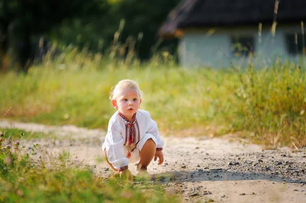 Маленький мальчик в украинской вышитой рубашке плачет в одиночестве на дороге — стоковое фото