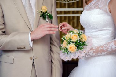 Gelin Damat'ın parmağında alyans koyarak