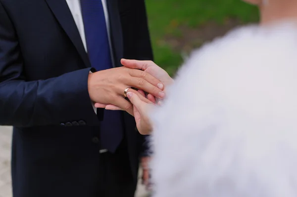 Noiva pondo uma aliança de casamento no dedo de um noivo — Fotografia de Stock