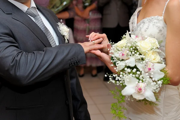 Novia poniendo un anillo de bodas en el dedo de un novio — Foto de Stock