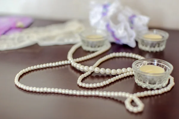 Perlas y velas sobre una mesa de madera — Foto de Stock