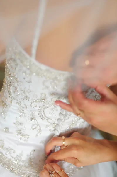 Bridesmaid is helping the bride to dress — Stock Photo, Image