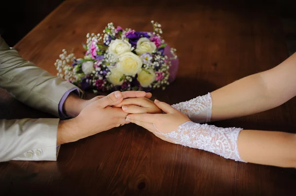 Brud- och brudgummen håller varandra i handen — Stockfoto