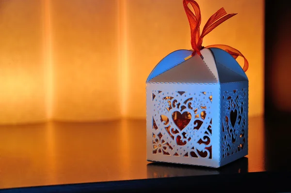 Decorative box with a heart cutout lit by a glowing candle with — Stock Photo, Image