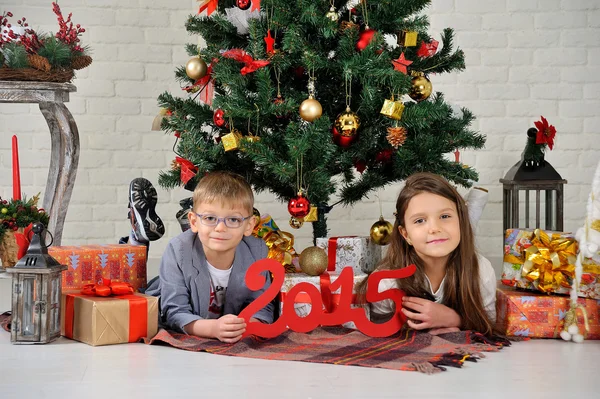 Hermano y hermana bajo el árbol de Navidad con regalos —  Fotos de Stock