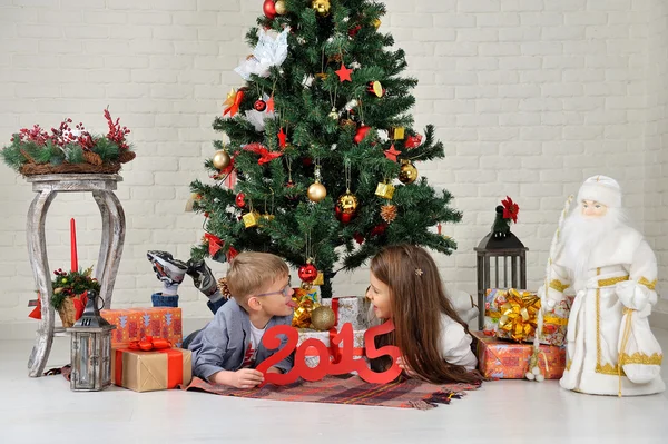 Hermano y hermana bajo el árbol de Navidad con regalos —  Fotos de Stock