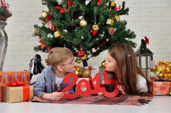 Hermano y hermana bajo el árbol de Navidad con regalos —  Fotos de Stock