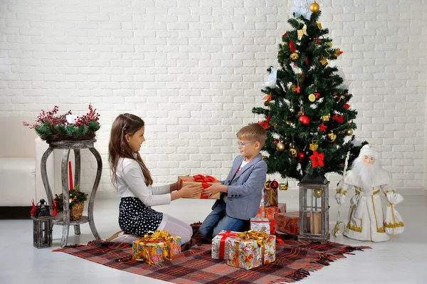 Hermano y hermana bajo el árbol de Navidad con regalos —  Fotos de Stock