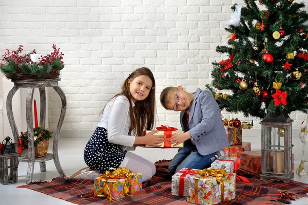 Hermano y hermana bajo el árbol de Navidad con regalos —  Fotos de Stock