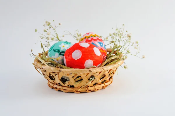Velikonoční vejce v košíku s seno na bílém pozadí — Stock fotografie