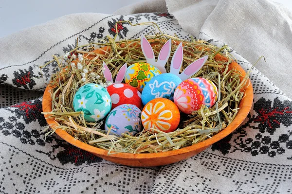 Huevos de Pascua en un plato con heno sobre fondo de lino — Foto de Stock