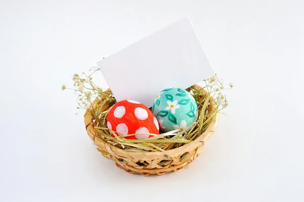 Huevos de Pascua coloridos en cesta y tarjeta en blanco — Foto de Stock