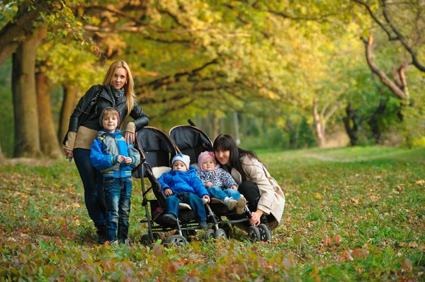 Madres con niños gemelos en un paseo por el parque de otoño — Foto de Stock