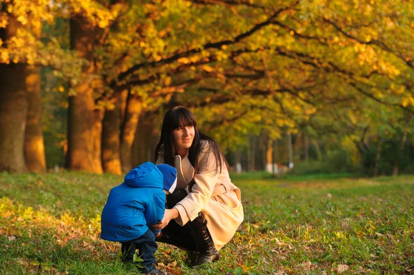 Madre con el niño en un paseo por el parque de otoño — Foto de Stock