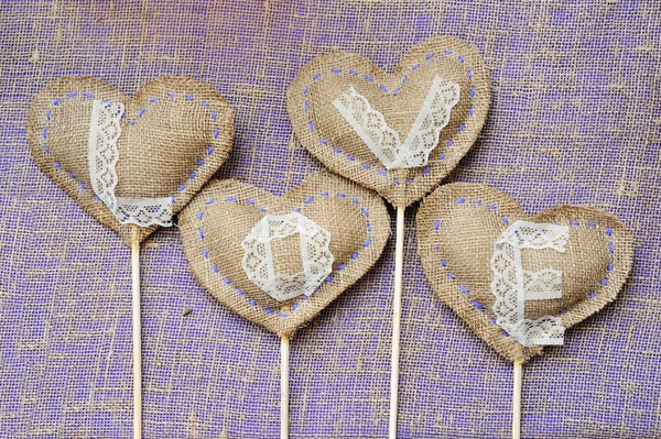 Ordet kärlek på lin och linne bakgrund hjärtan. Greeti — Stockfoto