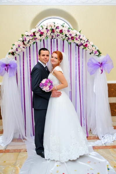 Bride and groom at a wedding ceremony under the arch — Stock Photo, Image