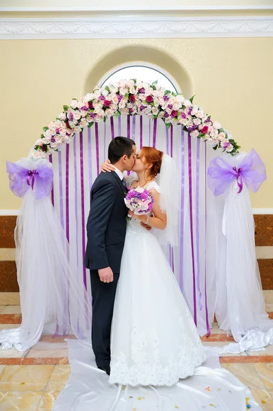 Невеста и жених на свадебной церемонии под аркой — стоковое фото
