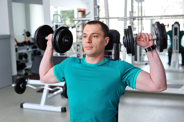 Man lifting dumbbells in a fitness club