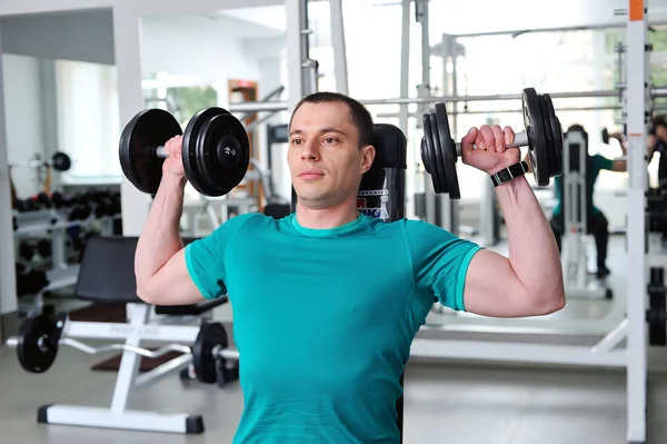 Uomo che solleva manubri in un fitness club — Foto Stock