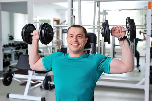 Uomo che solleva manubri in un fitness club — Foto Stock