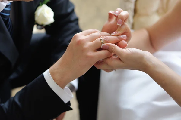 Braut steckt einem Bräutigam einen Ehering an den Finger — Stockfoto