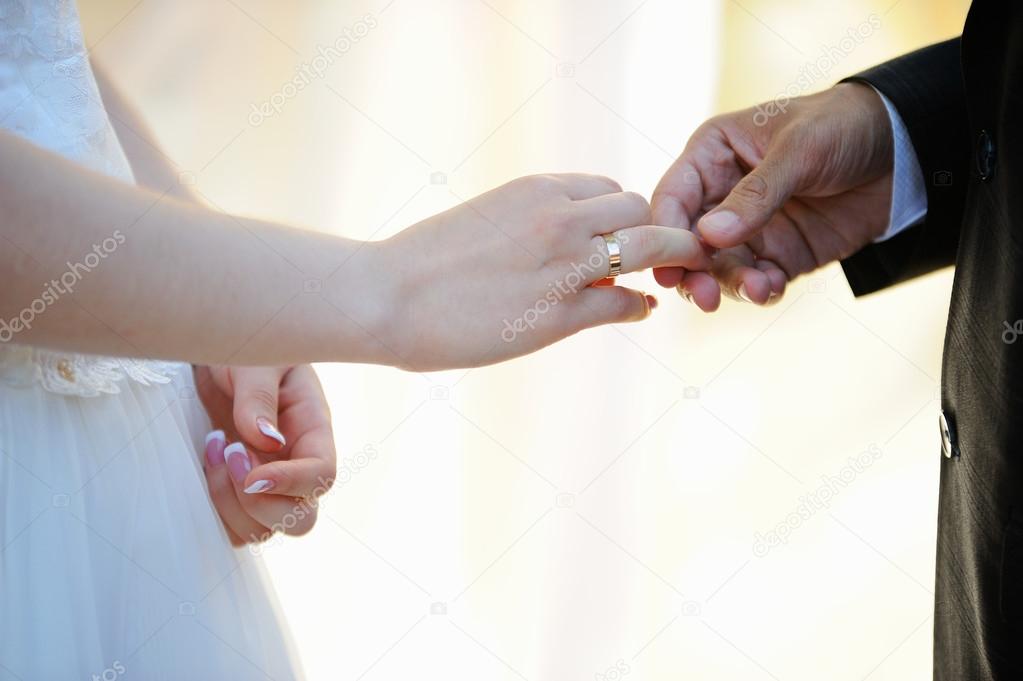 Groom putting ring on bride's finger