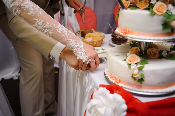 ウェディングレセプションで花嫁と新郎がウェディングケーキを切る — ストック写真