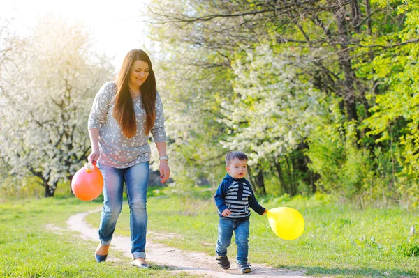 Madre e hijo caminando a lo largo del floreciente jardín de primavera — Foto de Stock