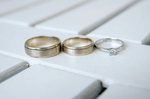 白色的木制背景上的结婚戒指 — 图库照片