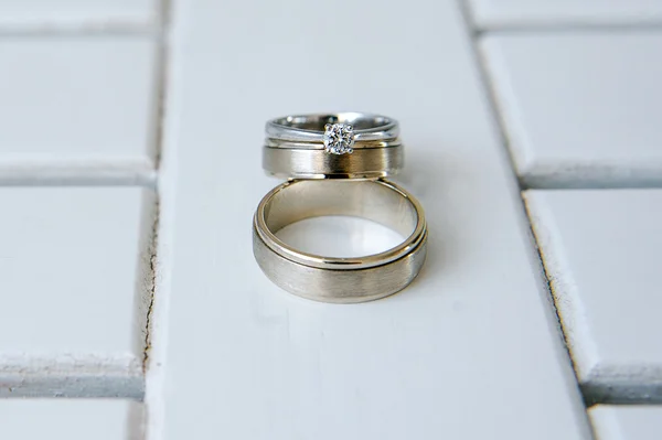 白色的木制背景上的结婚戒指 — 图库照片
