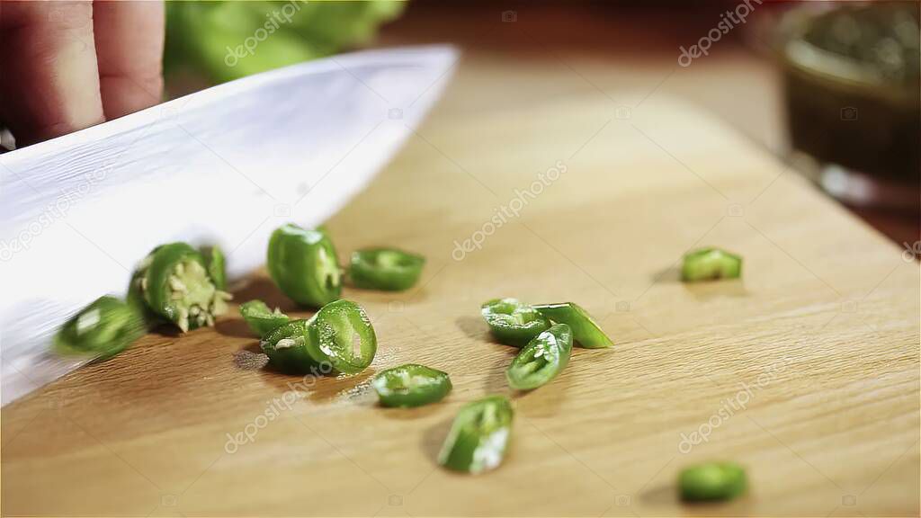 woman cutting green pepper on wooden board