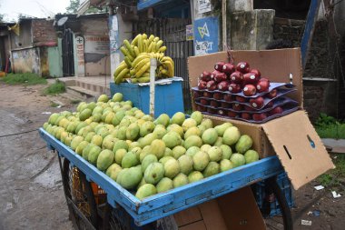 Muz, elma ve bir sürü mango. Meyveler Hint sokak pazarında satılmak üzere el arabasında ayarlandı. Yerel meyve pazarı.