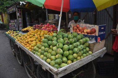 Hintli bir adam Hindistan sokak pazarında satılan meyveler (elma, mango ve muz).