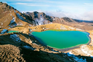 Stunning emerald blue lake in high magnitude of World's Heritage Tongariro National Park, Great Walk, smoking sulphur from ground of active volcano