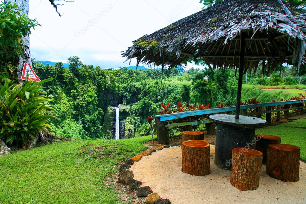 Colourful tropical paradise garden in Oceania, wooden shelter with palm thatch roof, jungle forest lookout, Sopoaga Falls resort in Samoa, Upolu Island