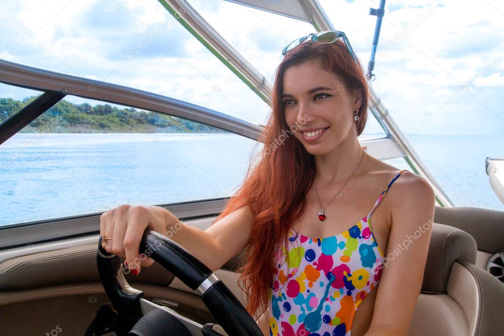 Beautiful hot young lady in colourful trendy bikini with nice smiling face sailing luxury boat on exotic vacation, portrait of sexy bikini woman boating, blue water and sandy beach on background