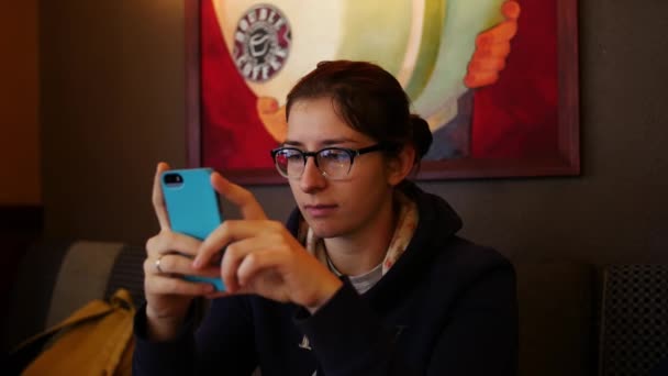 Mujer joven usando teléfono inteligente en la cafetería, disparo steadicam — Vídeos de Stock